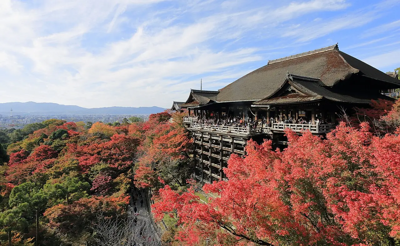 秋天的清水寺,木造舞台被紅葉包圍,遠方是京都市區