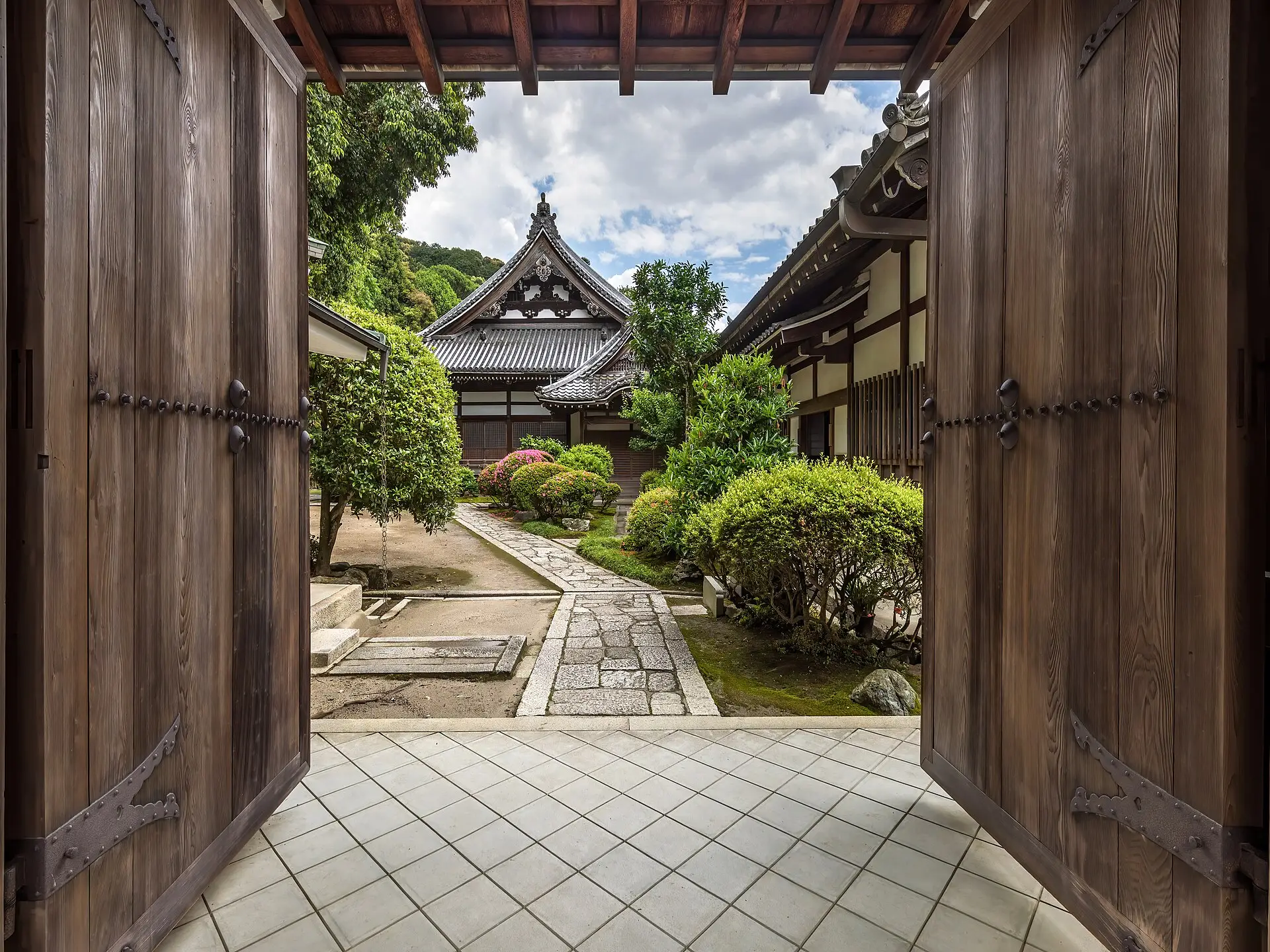京都知恩院境內一心院的木造庭門敞開,門後是鋪著碎石的庭園小徑